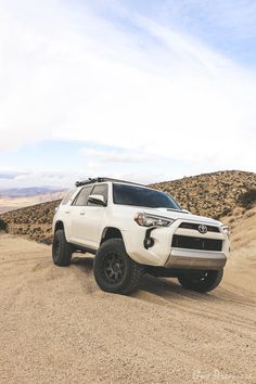 a white four - doored toyota suv driving down a dirt road