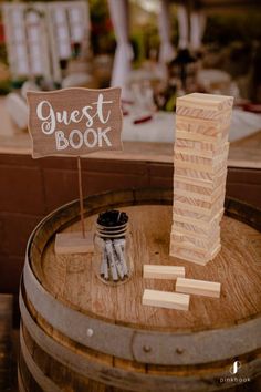 a wooden block tower sitting on top of a barrel next to a sign that says guest book