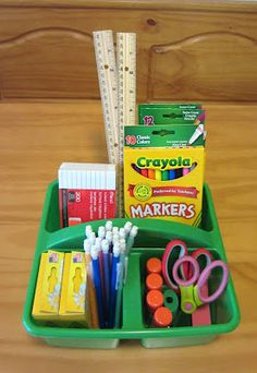 a green tray filled with school supplies on top of a wooden table