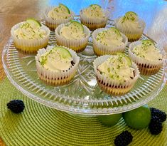 cupcakes with white frosting and blackberries sit on a glass platter