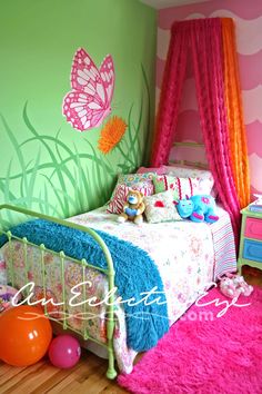 a child's bedroom decorated in pink, green and orange with butterflies on the wall