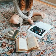 a woman sitting on the floor with an open book and electronic device in front of her