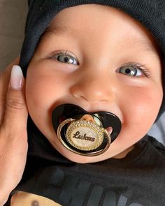 a baby with a pacifier in it's mouth is being held up to its face