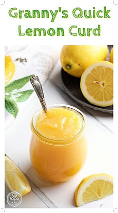 a jar filled with lemon curd sitting on top of a white table next to sliced lemons