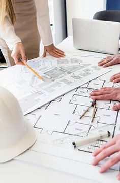 several people working on blueprints at a table with hard hats and pencils