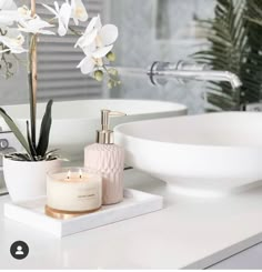 a bathroom sink with a candle and some flowers on it