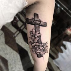 a cross and flowers tattoo on the arm