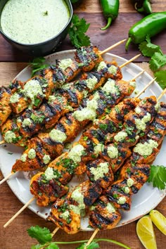 grilled chicken skewers with cilantro and lime sauce on a white plate