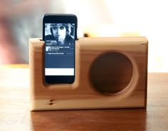 a cell phone sitting on top of a wooden device holder with an iphone in it