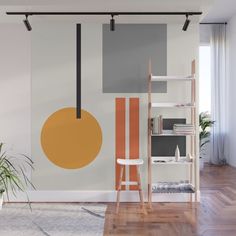 a living room with an orange and grey painting on the wall, white shelving unit and wooden flooring