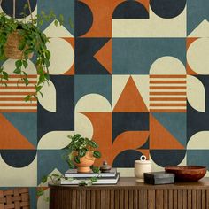 a table with some books and plants on top of it in front of a colorful wallpaper