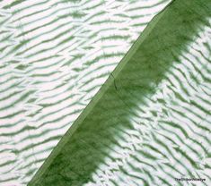 the shadow of an umbrella is cast on water ripples in green and white colors