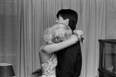 black and white photograph of a man hugging a woman in front of a tv set