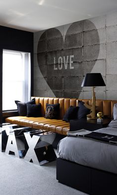 a bed room with a neatly made bed and a love sign on the wall