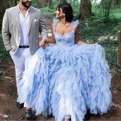 a man and woman are walking through the woods together wearing blue dresses with ruffles