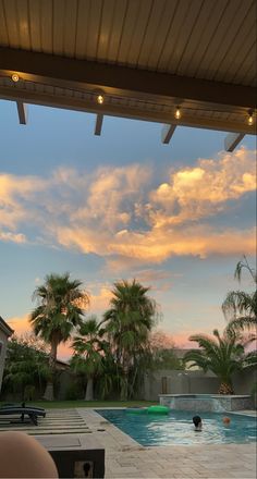 an outdoor swimming pool with lounge chairs and palm trees in the background at sunset or dawn