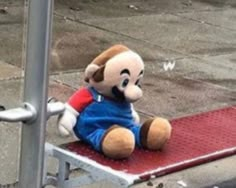 a stuffed animal sitting on top of a red metal step way next to a street