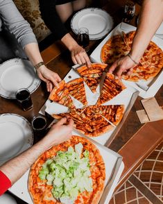 several people are eating pizza at a table