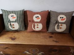 three pillows with snowmen on them sitting on a bench