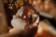 a person holding a glass ball in their hand with gold flecks on it