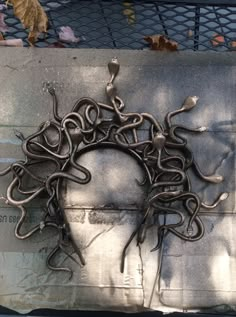 a piece of art that looks like it has been made out of metal and is hanging on the side of a fence