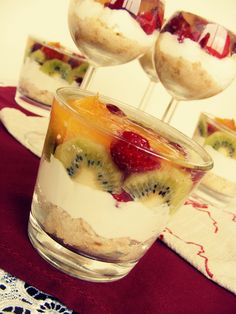 desserts in small glass bowls on a table with fruit and yogurt garnishes