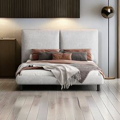 a large bed sitting on top of a hard wood floor next to a wall mounted lamp