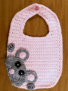 a crocheted pink bib with a gray mouse on it, sitting on a wooden surface