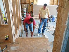 two men working on the floor in a house under construction