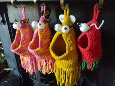 three crocheted birds hanging from hooks on a fireplace mantel with eyeballs