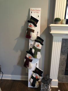 snowmen are hanging on the wall with hats and scarves attached to them in front of a fireplace