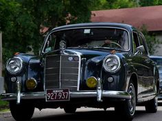 an old fashioned car is parked on the side of the road in front of a house