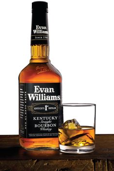 evan williams kentucky single barrel bourbon whiskey with ice in glass on wooden table against white background