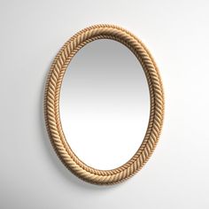 an oval rope mirror hanging on the wall with a white background and light colored walls