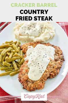 a white plate topped with meat covered in gravy next to green beans and mashed potatoes