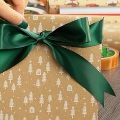 a person is holding a present wrapped in brown paper with green ribbon