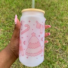 a person holding up a pink cup with candy canes and christmas decorations on it