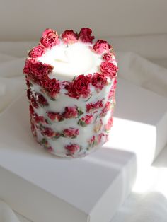 a white candle with red flowers on it