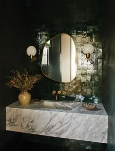 a bathroom with marble counter top and green tile on the wall, along with a vase filled with flowers