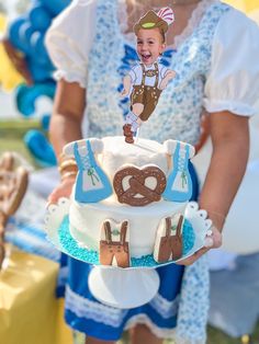 a woman holding a cake decorated with an image of a boy on top of it