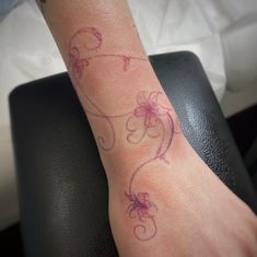 a person with a tattoo on their arm that has flowers and vines drawn on it