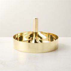 a gold plate on a white table with a metal holder in the shape of a cross