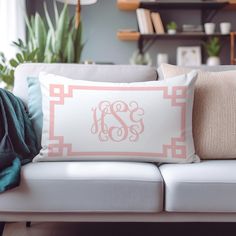 a white couch with two pillows and a pink monogrammed pillow sitting on top of it