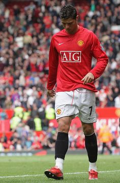 a man standing on top of a soccer field wearing a red shirt and white shorts