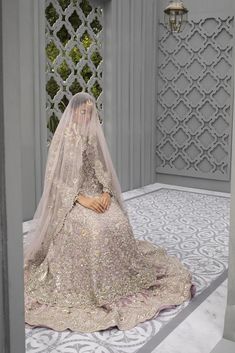 a woman in a wedding dress sitting on the floor with a veil over her head