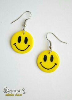 a pair of yellow earrings with a smiley face painted on the front and back of it