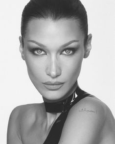 a black and white photo of a woman with tattoos on her arm, wearing a neck tie