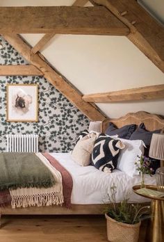 a bed sitting under a wooden beam in a bedroom next to a wallpapered wall