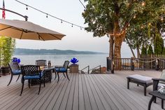 an outdoor deck with chairs and umbrellas overlooking the water on a sunny day at dusk