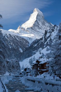 a mountain covered in snow next to a river